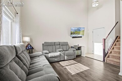Living area featuring a high ceiling, stairs, and wood finished floors