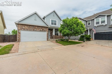 View of front of home featuring driveway, a garage, covered porch, and stone siding