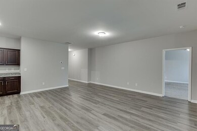 Unfurnished living room featuring light wood-type flooring and baseboards