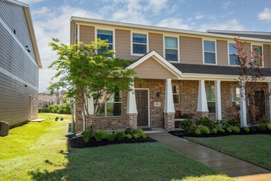 View of front of home featuring brick siding, a front yard, and covered porch