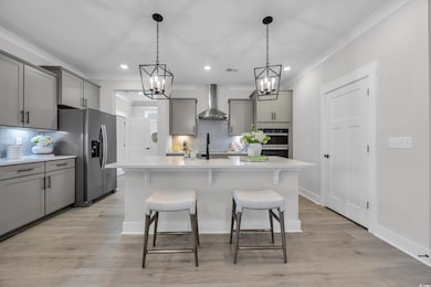Kitchen featuring gray cabinetry, tasteful backsplash, decorative light fixtures, appliances with stainless steel finishes, and a kitchen breakfast bar