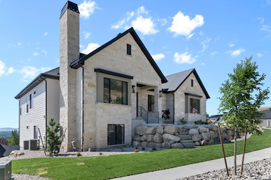 View of front facade with stone siding, a chimney, and a front lawn