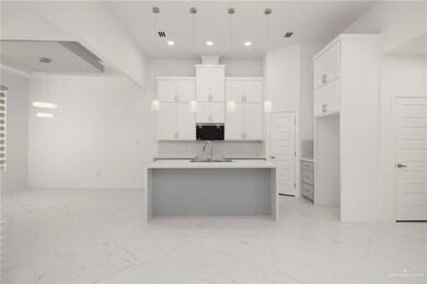 Kitchen with stainless steel microwave, a sink, backsplash, recessed lighting, and white cabinets