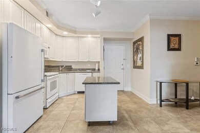 Kitchen with white appliances, white cabinets, dark stone counters, crown molding, and light tile patterned floors