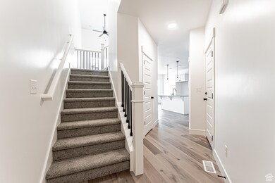 Stairway with wood finished floors and ceiling fan