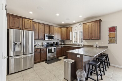 Kitchen featuring appliances with stainless steel finishes, a breakfast bar, light tile patterned floors, a peninsula, and recessed lighting