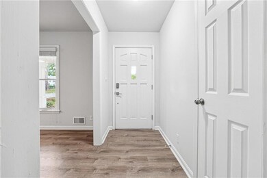 Foyer entrance with baseboards, visible vents, and wood finished floors