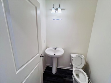 Bathroom featuring toilet, wood finished floors, baseboards, and a sink