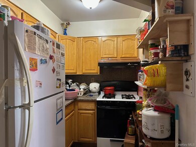 Kitchen with freestanding refrigerator, gas stove, under cabinet range hood, dark countertops, and brown cabinets