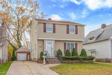 Colonial-style house featuring an outdoor structure, a front yard, a garage, driveway, and a chimney