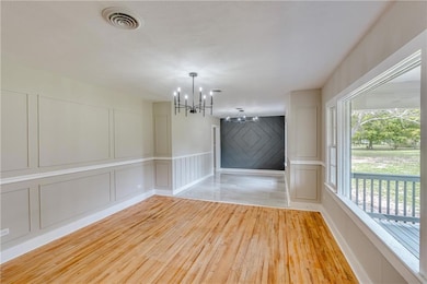 Unfurnished dining area with a decorative wall, light wood-style flooring, and a chandelier