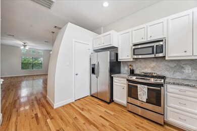 The kitchen opens to the dining area, providing the ideal flow from oven to table. The door pictured opens to a great pantry closet with built-in L-shaped shelving and large custom-built spice rack on the door interior. Additional highlights include beautiful hardwood flooring, tall ceilings, and recessed lighting.