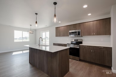 Kitchen with stainless steel appliances, light countertops, light wood finished floors, recessed lighting, and a center island with sink
