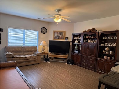 Living area with visible vents, a ceiling fan, and