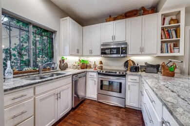 Kitchen with open shelves, white cabinets, appliances with stainless steel finishes, and dark wood-type flooring