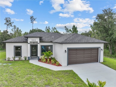 Prairie-style house with stucco siding, a garage, and a front yard