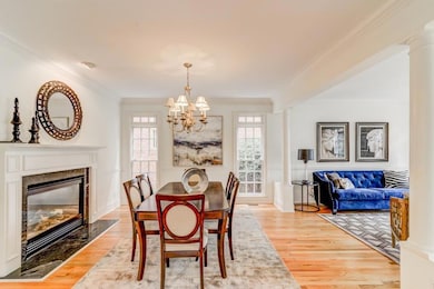Dining area featuring a chandelier, crown molding, healthy amount of natural light, light wood finished floors, and a high end fireplace