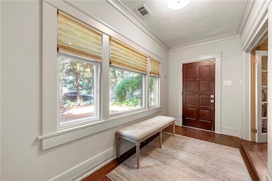 Foyer entrance with dark wood-style floors and ornamental molding