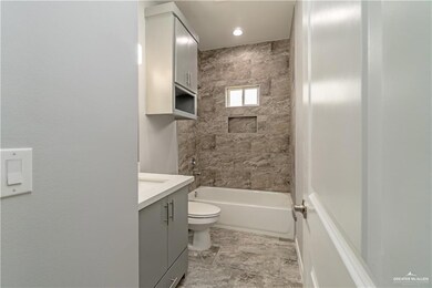 Full bathroom with vanity, toilet, tile floors, and tiled shower / bath combo