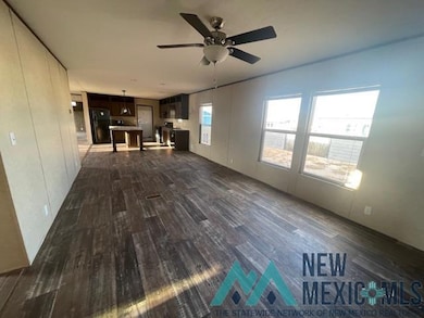 Unfurnished living room featuring dark wood-type flooring and a ceiling fan