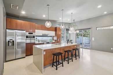 The kitchen is a masterpiece of form and function, featuring sleek quartz countertops with a waterfall edge on the oversized central island.