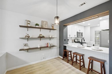 Dining area off the kitchen featuring floating shelves for storage or display, modern lighting, and view into the kitchen.