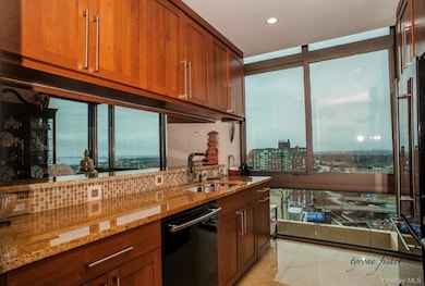 Kitchen with light stone counters, dishwasher, high end refrigerator, brown cabinetry, and recessed lighting
