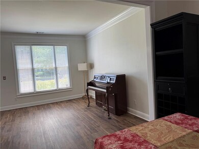 Bedroom featuring baseboards, wood finished floors, multiple windows, and crown molding