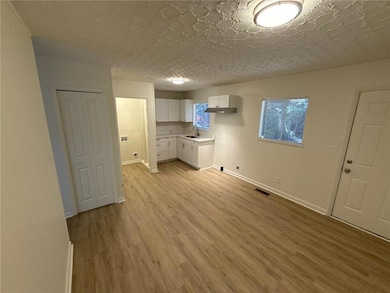 Laundry room with light wood-style flooring, a textured ceiling, cabinet space, and hookup for a washing machine