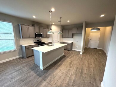 Kitchen featuring sink, hanging light fixtures, hardwood / wood-style floors, a center island with sink, and appliances with stainless steel finishes
