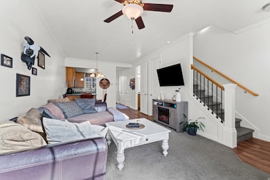 Living room with ornamental molding, stairway, ceiling fan, carpet, and wood finished floors