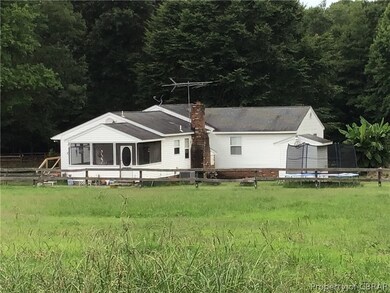Back of house featuring a trampoline, a lawn, and