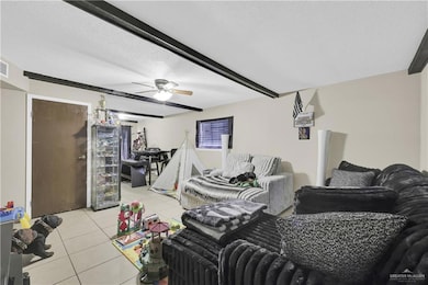 Living area featuring light tile patterned floors, a textured ceiling, a ceiling fan, and beamed ceiling