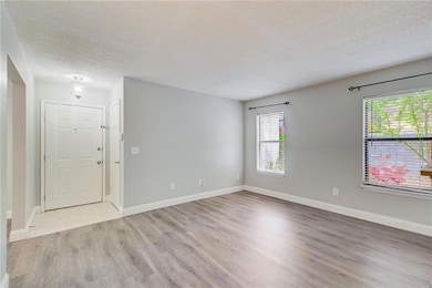 Unfurnished room with baseboards, wood finished floors, and a textured ceiling