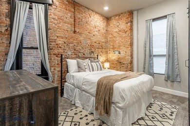 Carpeted bedroom featuring brick wall