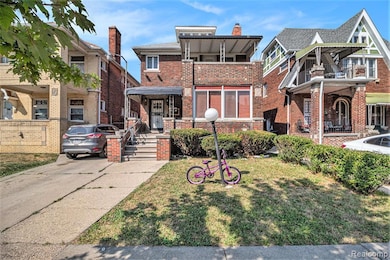 View of front of house featuring brick siding, a front yard, and a balcony