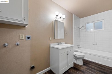 Bathroom with dark wood-type flooring, shower / washtub combination, a textured wall, and vanity