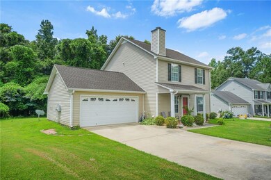 Traditional-style home with an attached garage, a chimney, driveway, and a front lawn