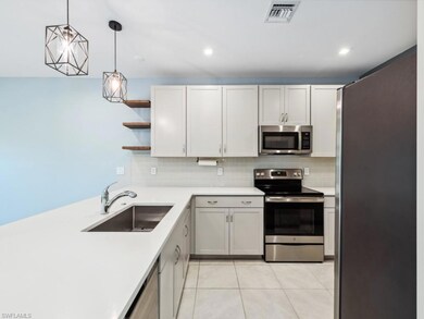 Kitchen featuring sink, white cabinetry, hanging l