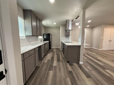 Kitchen with black electric cooktop, a sink, venti