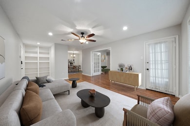 Virtually staged living area with built-in shelving, wood-look floors, and open flow into the dining room and study. Bright, versatile layout offers space for entertaining and everyday living
