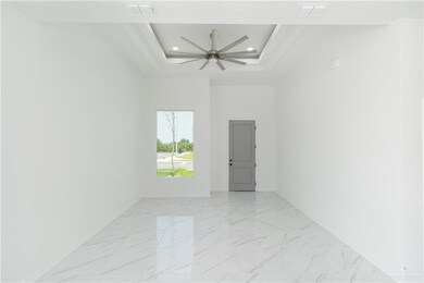 Unfurnished room featuring ceiling fan, light tile patterned floors, and a tray ceiling