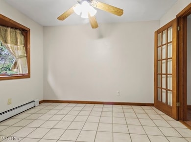 Spare room with light tile patterned floors, a baseboard radiator, and a ceiling fan