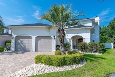 View of front facade featuring a chimney, a garage, decorative driveway, a front lawn, and stucco siding