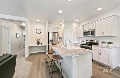 Kitchen with appliances with stainless steel finishes, a breakfast bar, light wood-style floors, a kitchen island with sink, and light stone countertops