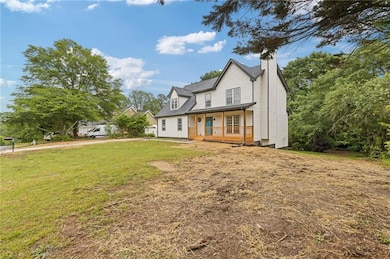 Back of house with a lawn, a chimney, and a porch