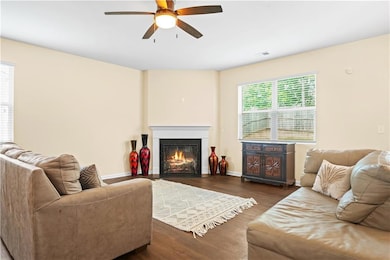 Living area featuring ceiling fan, dark wood-style