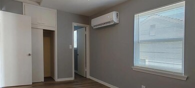 Unfurnished bedroom featuring dark hardwood / wood-style flooring, a wall unit AC, and a closet