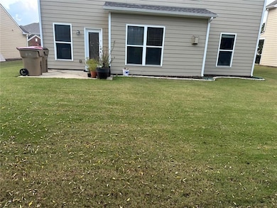 Back of property featuring a lawn, a patio, and a shingled roof