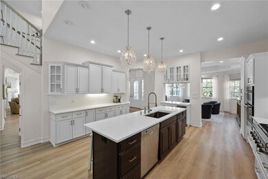 Kitchen featuring a sink, stainless steel appliances, an island with sink, light countertops, and a chandelier